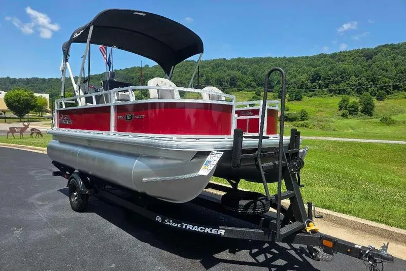 The Image of 2026 Sun Tracker Bass Buggy 16 XL Select pontoon boat on trailer, scenic background. - 0