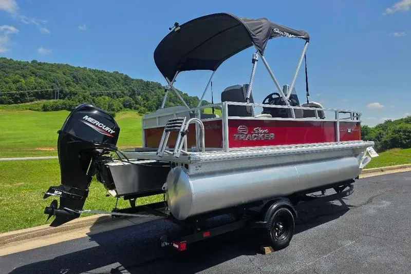 Slide: The Image of 2026 Sun Tracker Bass Buggy 16 XL Select pontoon boat with Mercury engine on trailer. - 2