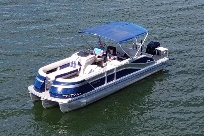 Slide: The Image of 2022 Harris Grand Mariner 250 pontoon boat cruising on a lake with blue canopy. - 4