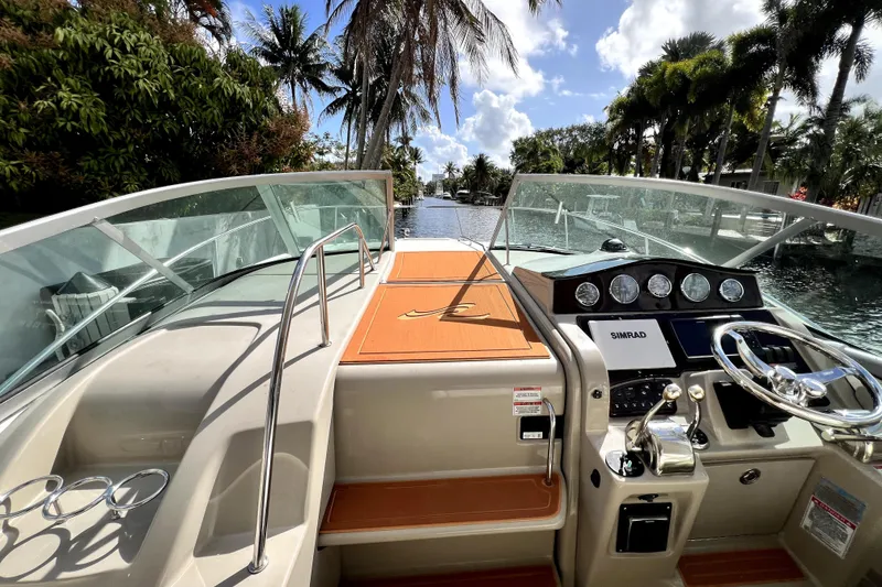 Slide: The Image of 2007 Sea Ray Sundancer 310 cockpit with steering wheel, dashboard, and tropical background. - 49