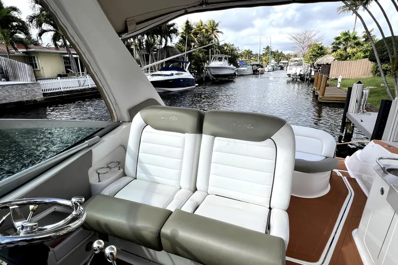 Slide: The Image of 2007 Sea Ray Sundancer 310 boat interior with plush seating, steering wheel, and canal view. - 54