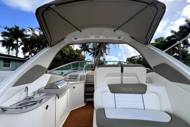 Slide: The Image of 2007 Sea Ray Sundancer 310 interior with seating, kitchenette, and canopy under a blue sky. - 59