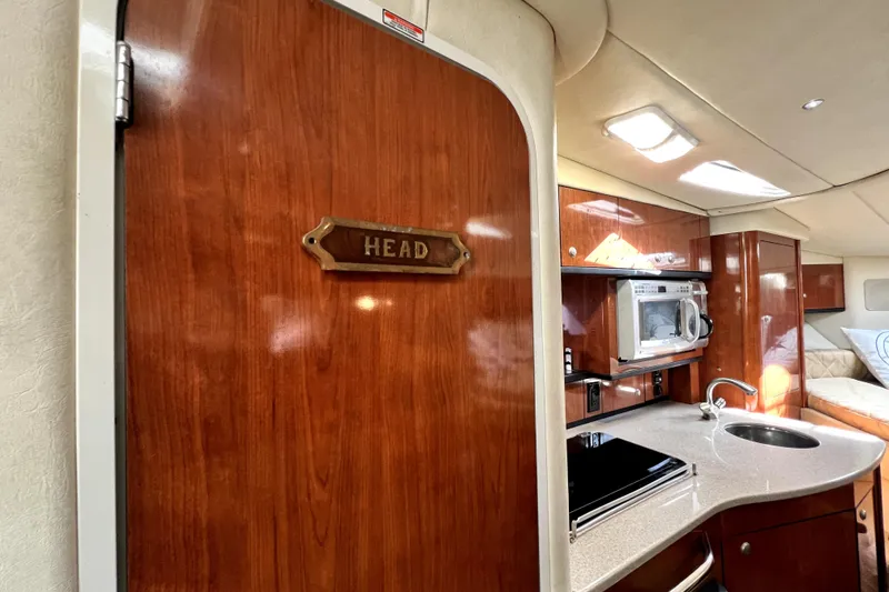 Slide: The Image of Interior of 2007 Sea Ray Sundancer 310 yacht, featuring kitchenette and wooden door labeled "Head". - 61
