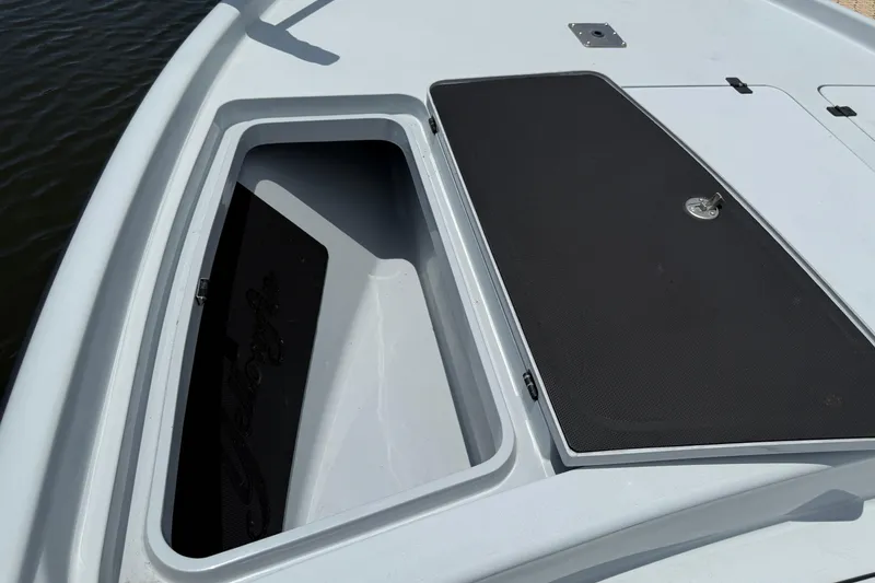 Slide: The Image of 2017 Yellowfin 24 Bay CE boat storage compartment, open on deck, near water. - 16