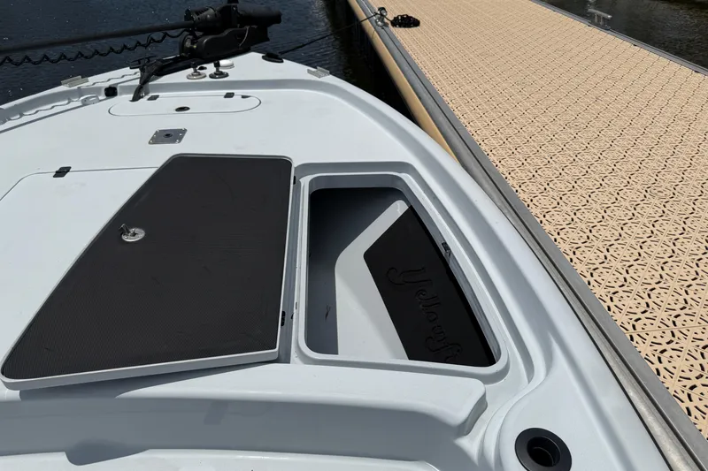 Slide: The Image of 2017 Yellowfin 24 Bay CE boat deck with open storage compartment near dock. - 17