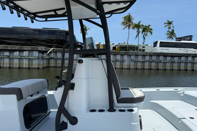 Slide: The Image of 2017 Yellowfin 24 Bay CE boat interior with seating and console, docked near palm trees. - 8