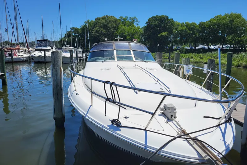 Slide: The Image of 1995 Sea Ray Sundancer 370 docked at a marina, surrounded by other boats and lush greenery. - 1