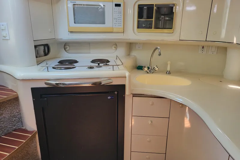 Slide: The Image of 1995 Sea Ray Sundancer 370 yacht kitchen with stove, microwave, sink, and storage cabinets. - 14