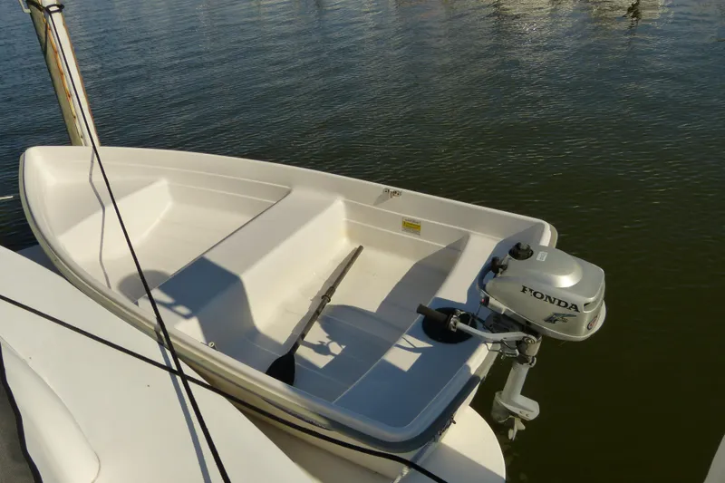 Slide: The Image of Small white boat with Honda outboard motor docked on calm water. - 27
