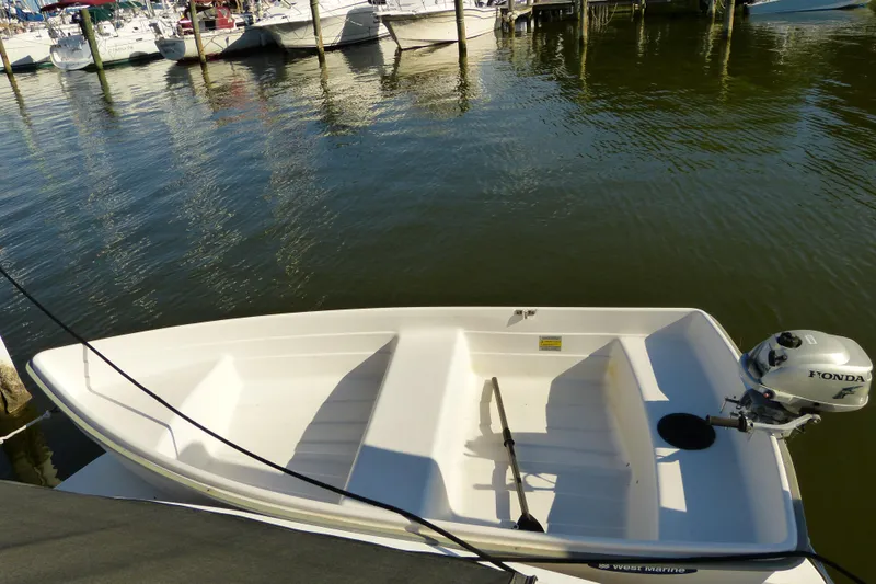 Slide: The Image of Small white boat with Honda outboard motor docked at marina, surrounded by water and other boats. - 59