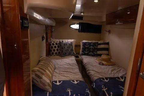 Slide: The Image of 2008 Regal Commodore 3860 cabin with twin beds, nautical-themed bedding, and decorative pillows. - 8