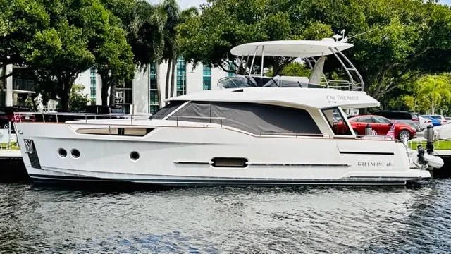 The Image of 2022 Greenline 48 Flybridge yacht with hardtop, docked by lush greenery. - 0