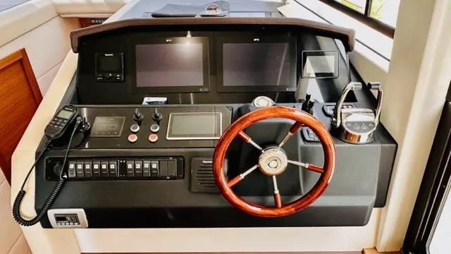 Slide: The Image of 2022 Greenline 48 Flybridge helm with dual screens, wooden steering wheel, and control panel. - 13