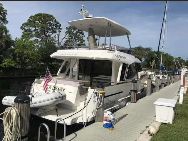 Slide: The Image of 2022 Greenline 48 Flybridge yacht docked, featuring hardtop and American flag. - 39