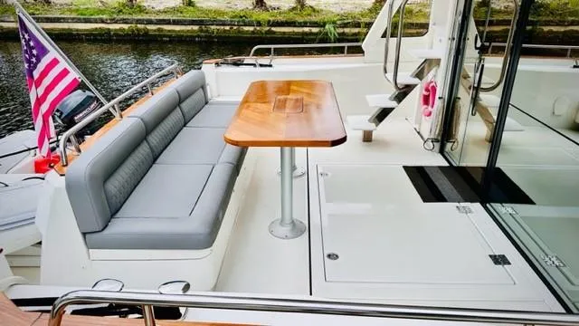 Slide: The Image of 2022 Greenline 48 Flybridge yacht deck with seating, table, and American flag. - 5