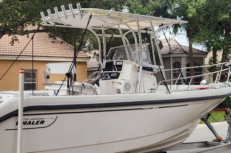 The Image of 1998 Boston Whaler 230 Outrage boat on trailer, parked near residential area. - 0