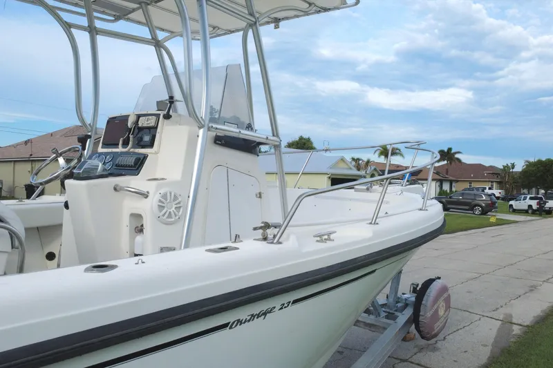 Slide: The Image of 1998 Boston Whaler 230 Outrage boat on trailer, parked in residential area under cloudy sky. - 16