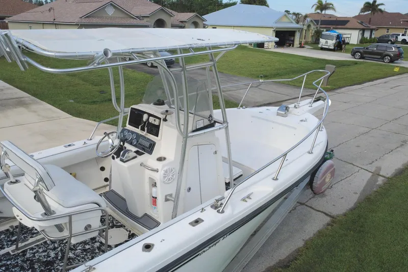 Slide: The Image of 1998 Boston Whaler 230 Outrage boat parked in residential driveway, featuring center console and T-top. - 17