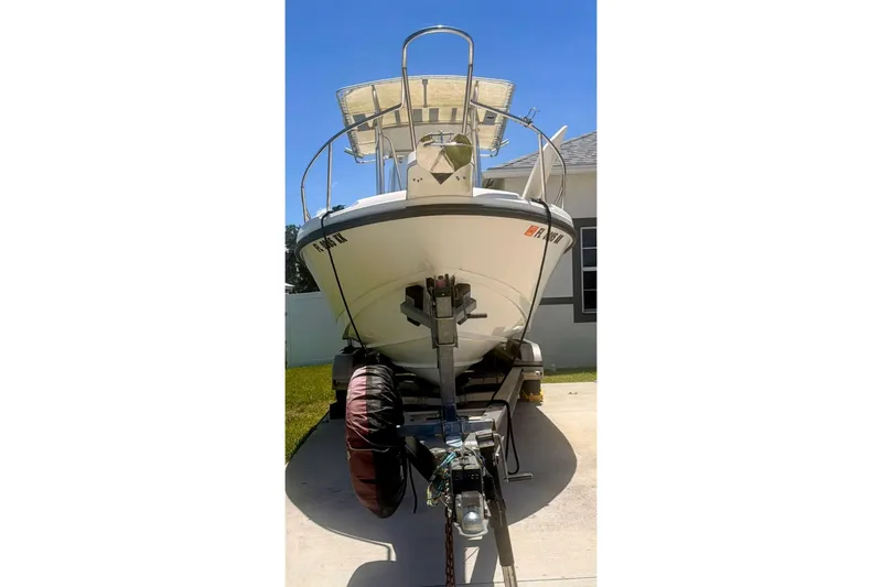 Slide: The Image of 1998 Boston Whaler 230 Outrage boat on trailer, parked in driveway under clear blue sky. - 3