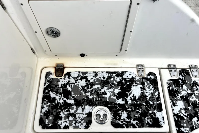 Slide: The Image of 1998 Boston Whaler 230 Outrage deck with camo-patterned flooring and storage hatch. - 32