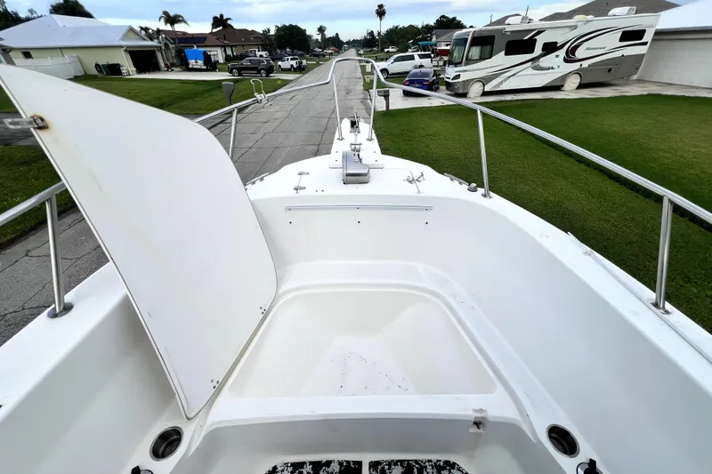 Slide: The Image of 1998 Boston Whaler 230 Outrage boat deck with open storage compartment, parked in residential area. - 74