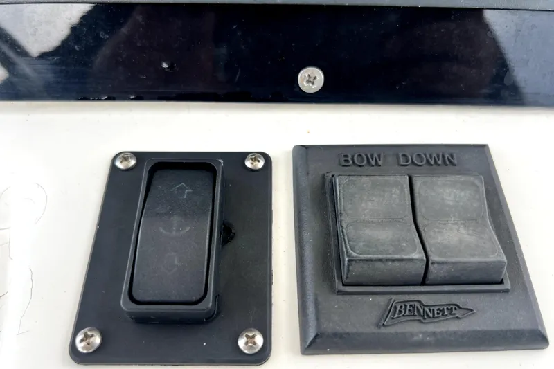 Slide: The Image of Boston Whaler 230 Outrage 1998 boat controls, featuring Bennett trim tab switches. - 82