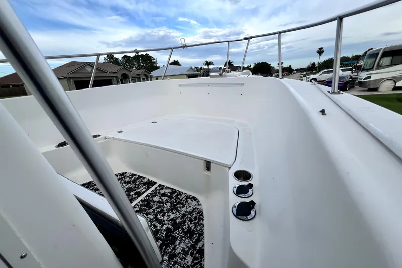Slide: The Image of 1998 Boston Whaler 230 Outrage boat deck with white interior and railing, under a cloudy sky. - 95