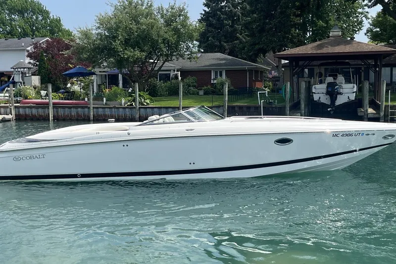 The Image of 2007 Cobalt 343 boat docked on a serene waterfront, surrounded by lush greenery. - 0