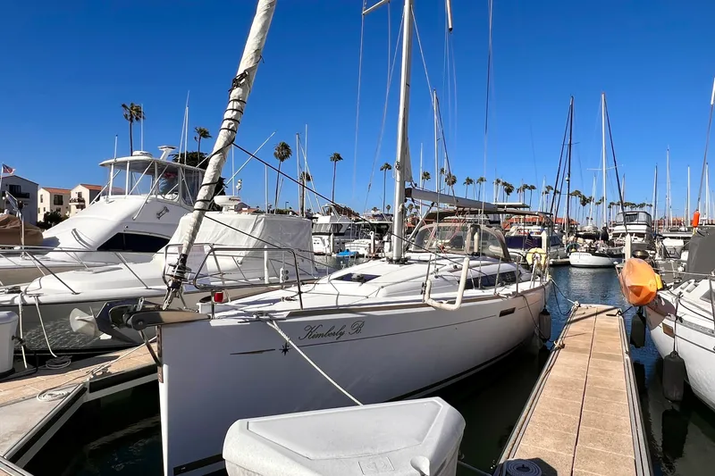 The Image of 2015 Jeanneau Sun Odyssey 379 sailboat docked in a marina under clear blue skies. - 0
