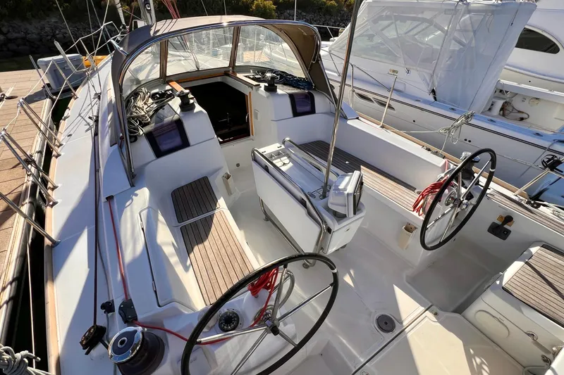 Slide: The Image of 2015 Jeanneau Sun Odyssey 379 sailboat cockpit with dual steering wheels and teak seating. - 12