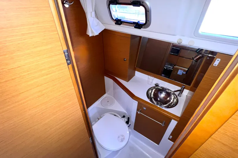 Slide: The Image of Compact bathroom in 2015 Jeanneau Sun Odyssey 379 yacht with sink, toilet, and wooden cabinetry. - 39