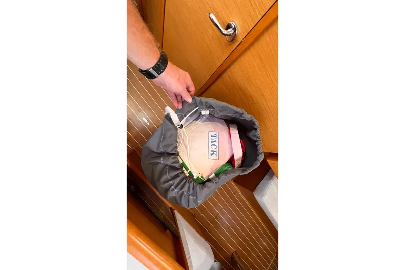 Slide: The Image of Hand holding a sail bag labeled "TACK" inside a 2015 Jeanneau Sun Odyssey 379 yacht. - 49