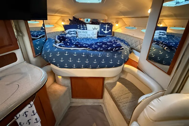 Slide: The Image of Interior of 2001 Sea Ray 340 Sundancer with nautical-themed bedding and cozy cabin space. - 24