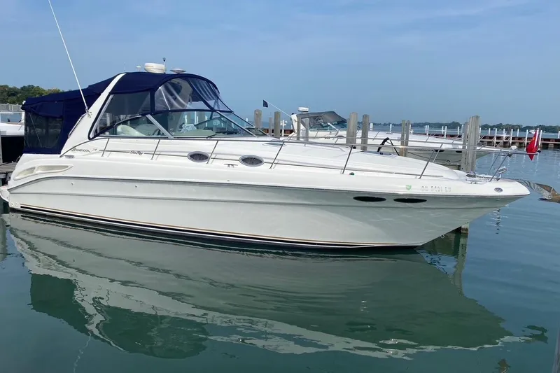 The Image of 2001 Sea Ray 340 Sundancer boat docked on calm water, featuring a sleek white design. - 0