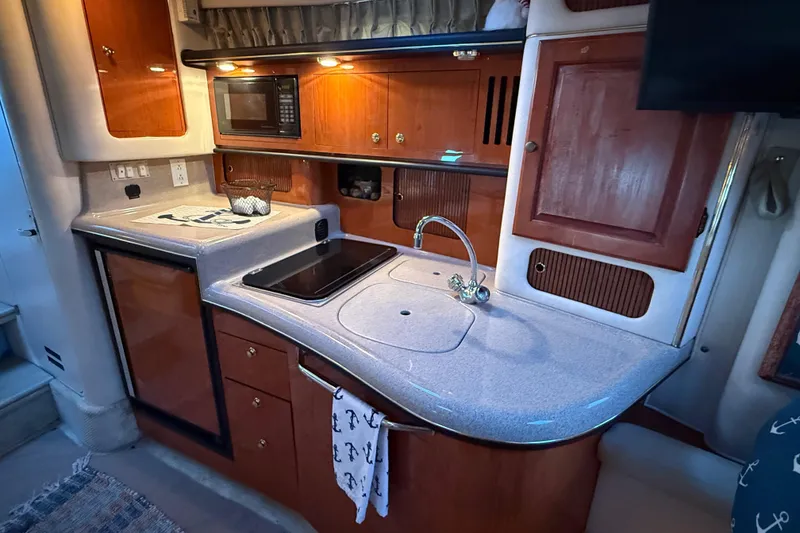 Slide: The Image of 2001 Sea Ray 340 Sundancer kitchen with wood cabinetry, sink, and microwave. - 22