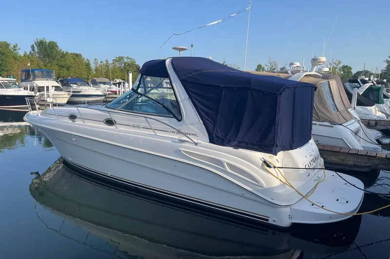 Slide: The Image of 2001 Sea Ray 340 Sundancer boat docked at marina, featuring blue canopy and sleek design. - 2