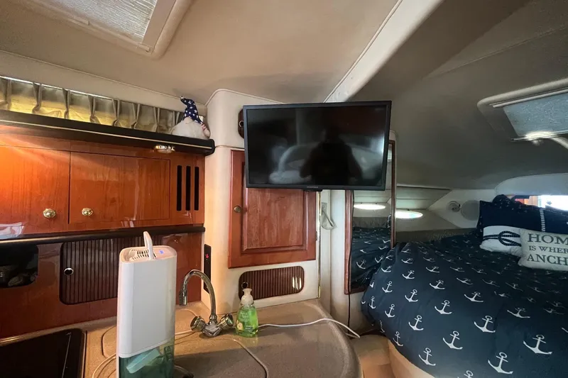 Slide: The Image of 2001 Sea Ray 340 Sundancer cabin interior with kitchenette, TV, and nautical-themed bedding. - 28