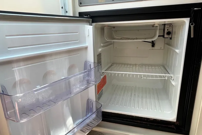 Slide: The Image of Open refrigerator inside a 2002 Formula 330 Sun Sport boat, showing empty shelves and door compartments. - 27