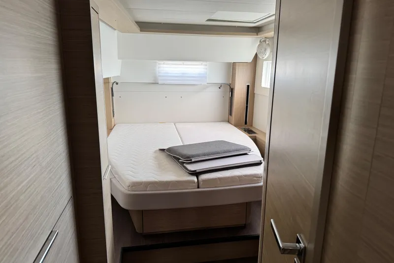 Slide: The Image of 2025 Lagoon 46 yacht cabin with a neatly made bed and modern interior design. - 26