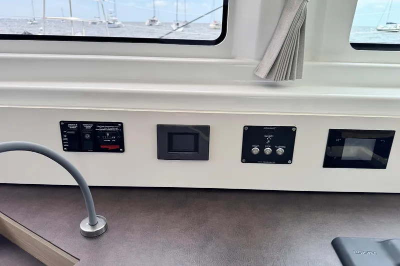 Slide: The Image of Control panel inside a 2025 Lagoon 46 yacht, featuring various switches and displays. - 28