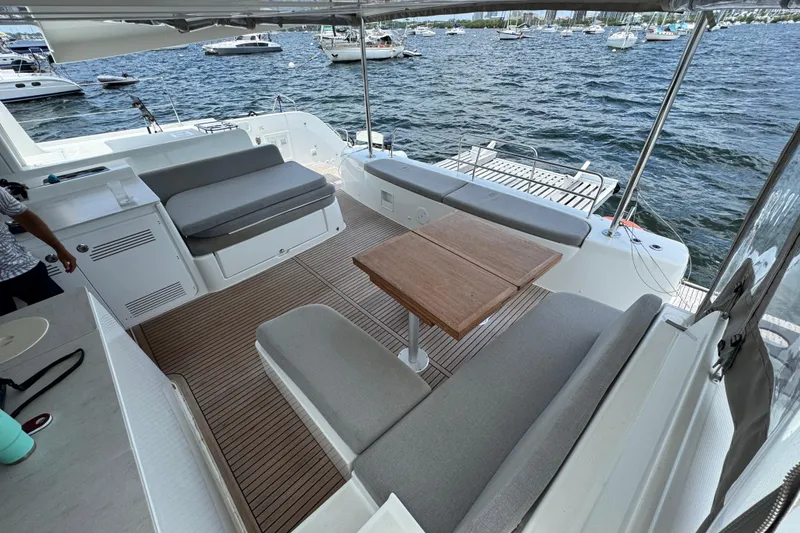 Slide: The Image of Spacious deck of 2025 Lagoon 46 catamaran with seating and table, overlooking marina. - 34