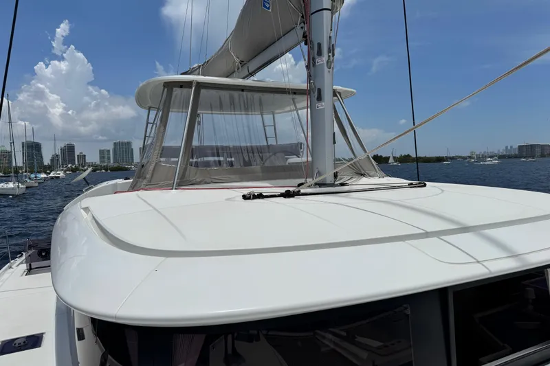 Slide: The Image of 2025 Lagoon 46 catamaran docked in a marina with city skyline in background. - 36