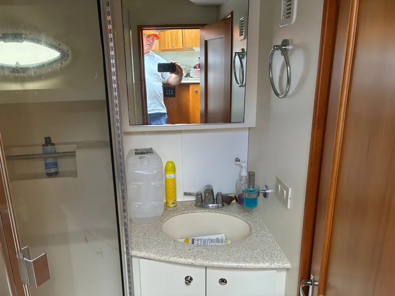 Slide: The Image of Bathroom in a yacht with sink, mirror, and shower. A person is visible in the mirror. - 35
