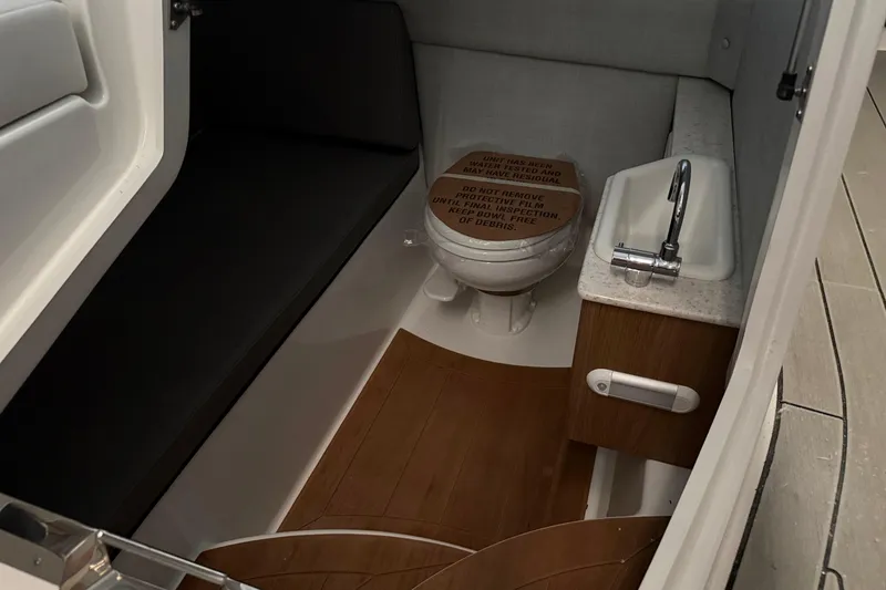 Slide: The Image of Interior of 2026 Yamaha Boats 295SD featuring a compact bathroom with toilet and sink. - 18