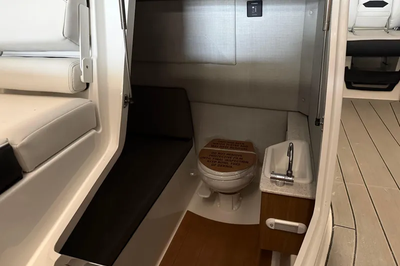 Slide: The Image of Interior of 2026 Yamaha Boats 295SD featuring compact bathroom with toilet and sink. - 19