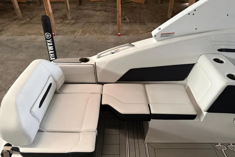 Slide: The Image of 2026 Yamaha Boats 295SD interior seating with white upholstery and cup holders. - 7