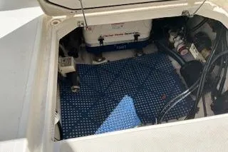 Slide: The Image of 2019 Pursuit OS 325 Offshore engine compartment with visible components and blue mat. - 10