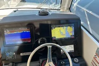 Slide: The Image of 2019 Pursuit OS 325 Offshore helm with dual navigation screens and steering wheel. - 11