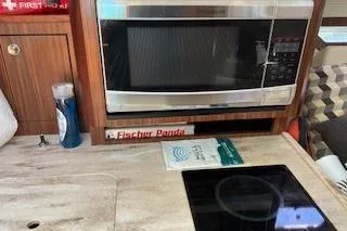 Slide: The Image of 2019 Pursuit OS 325 Offshore kitchen with microwave and induction cooktop. - 15