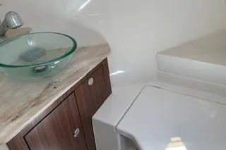 Slide: The Image of 2019 Pursuit OS 325 Offshore bathroom with glass sink and wooden cabinetry. - 17